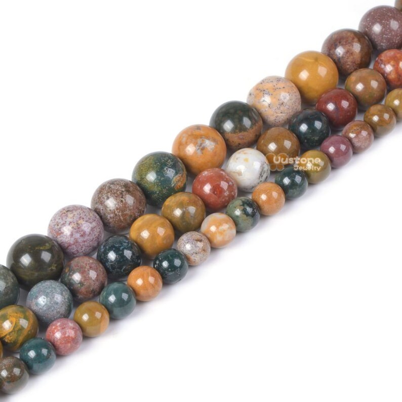 Pu&ograve; includere: Una collana di perline rotonde in pietra naturale multicolore. Le perline sono un mix di verde, marrone, giallo e rosso. Le perline sono di diverse dimensioni e sono disposte in un motivo sfumato.