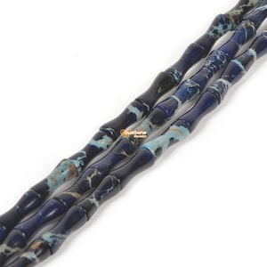 May include: A strand of blue and white bamboo-shaped gemstone beads. The beads have a marbled pattern and are strung together on a clear thread.