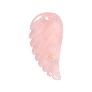 Puede incluir: Un colgante de ala de ángel de cuarzo rosa. El ala está tallada con un patrón detallado y tiene un agujero en la parte superior para sujetarlo a un collar o pulsera.