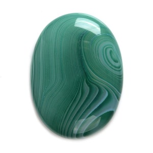 Puede incluir: Una piedra de ágata verde con un patrón de remolino. La piedra tiene forma ovalada y está pulida.