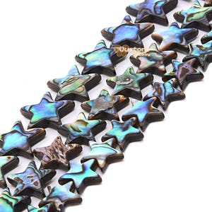 Puede incluir: Cadenas de cuentas en forma de estrella con tonos iridiscentes azules, verdes y marrones. Estas cuentas tienen un acabado pulido y brillante y están dispuestas en diagonal. Adecuadas para la creación de joyas o manualidades.