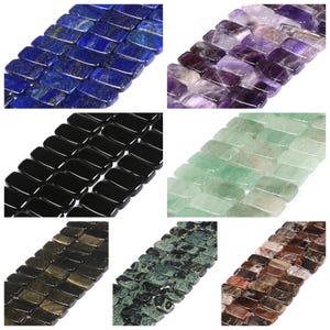 May include: A collection of seven strands of rectangular gemstone beads in various colors and textures, including deep blue lapis lazuli, purple amethyst, solid black onyx, pale green aventurine, metallic gold, mottled dark green, and brown wood grain.