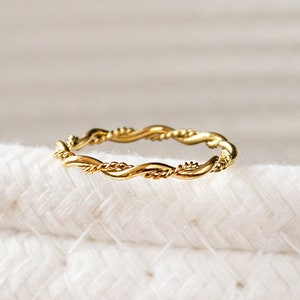 Può includere: Un anello a fascia ritorta dorata. L'anello è semplice e delicato.