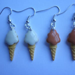 May include: Four pairs of ice cream cone earrings. Two pairs are white ice cream with a brown cone and two pairs are brown ice cream with a brown cone.
