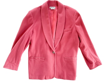 May include: A pink blazer with a shawl collar and a single button closure. The blazer has two pockets on the front and is made of a soft, textured fabric.