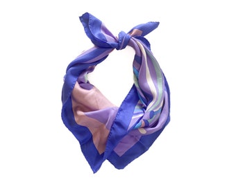 May include: A square silk scarf in shades of blue, purple, and pink, knotted at the top. The scarf features a geometric pattern with curved lines and a solid blue border. The scarf is displayed against a white background.
