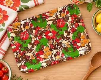 May include: A rectangular serving tray featuring a vibrant floral pattern with red, orange, yellow, and brown flowers set against a bright green background. The tray has rounded corners and a glossy finish, displaying a dense, repeating botanical design.