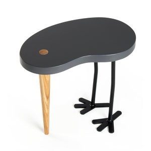 May include: A gray, kidney-shaped side table with a wooden leg and two black metal legs shaped like bird feet.