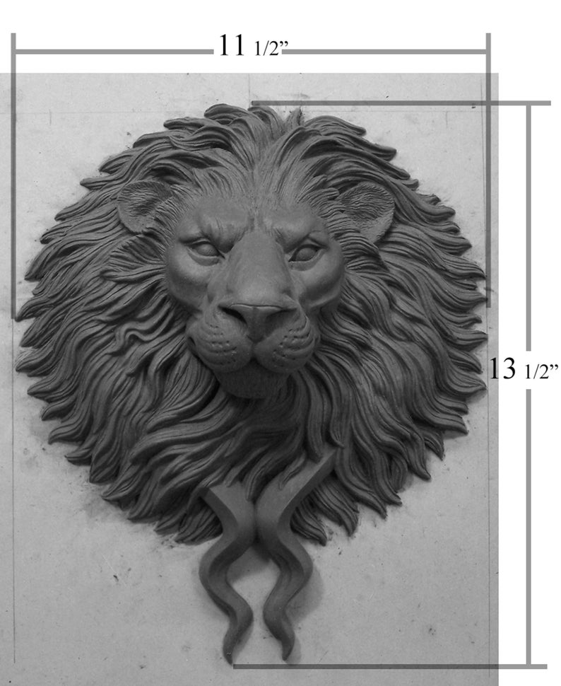 Pode incluir: Escultura de cabe&ccedil;a de le&atilde;o em tons de cinza, medindo 29 cm de largura e 34 cm de altura. A escultura apresenta uma juba detalhada, um nariz proeminente e elementos curvos estilizados na base. A express&atilde;o do le&atilde;o &eacute; estoica.