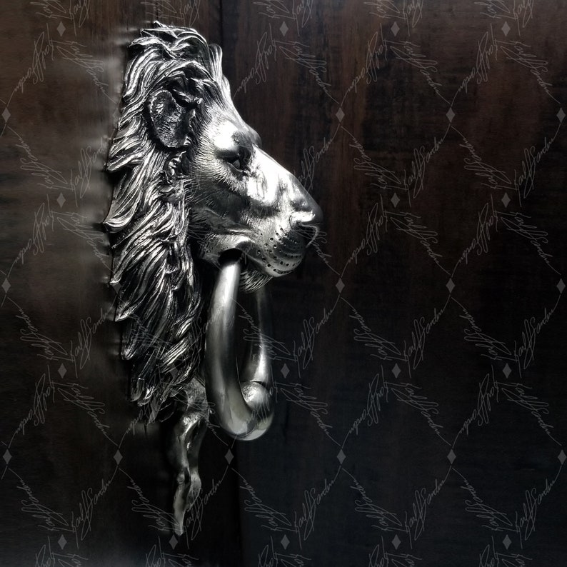 May include: A silver lion's head door knocker with a ring handle. The knocker is mounted on a dark wooden door.