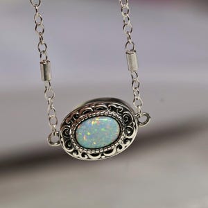May include: A silver chain necklace with a silver oval pendant featuring a white opal gemstone.