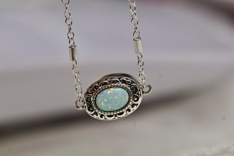 May include: A silver chain necklace with a silver oval pendant featuring a white opal gemstone.