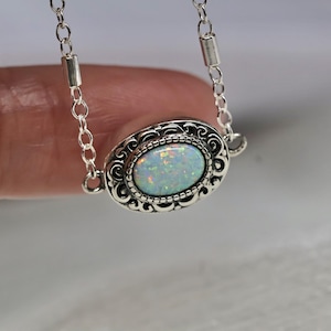 May include: A silver chain necklace with a white opal gemstone set in an ornate silver pendant.