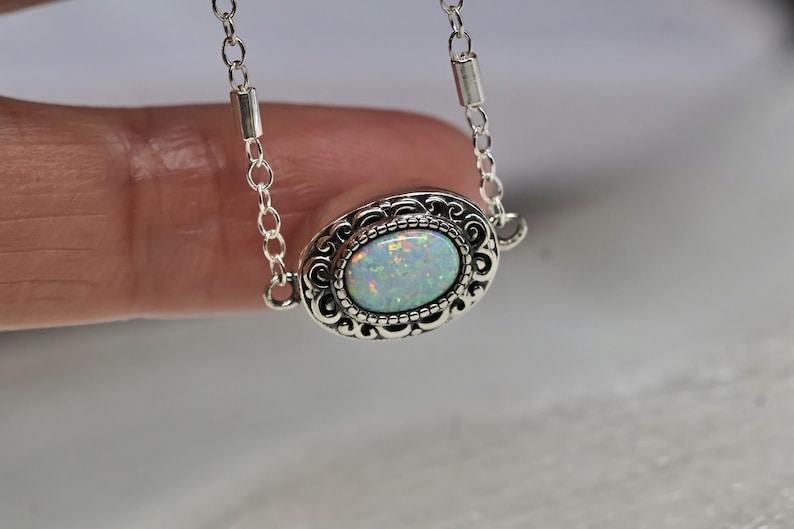 May include: A silver chain necklace with a white opal gemstone set in an ornate silver pendant.