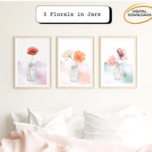Op de afbeelding: Drie ingelijste bloemenprints met aquarelbloemen in glazen potten. De prints hebben een licht houten frame en zijn tegen een witte muur geplaatst. De tekst "3 Florals in Jars" staat boven de prints. De prints zijn gelabeld "Digital Downloads".