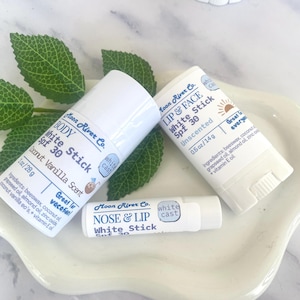 May include: Three white cylindrical sunscreen sticks by Moon River Co. The largest is a 1oz/28g Body White Stick SPF 30 in Coconut Vanilla Scent. The medium is a 0.5oz/14g Lip & Face White Stick SPF 30. The smallest is a Nose & Lip White Stick SPF 30.