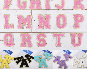 May include: Pink felt letters of the alphabet with gold trim, arranged in rows from A to U.  The letters are approximately 2 inches tall.  There are also smaller versions of the letter A in yellow, black, turquoise, purple, and white.