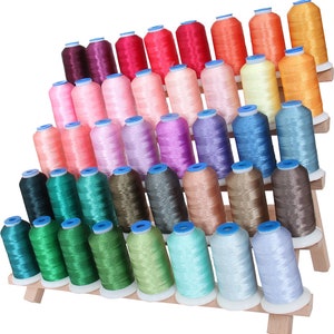 May include: A wooden thread rack with multiple spools of colorful thread. The rack is tiered and holds a variety of colors, including pink, blue, green, and brown.