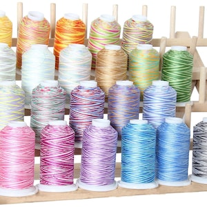 May include: A set of 20 colorful spools of thread, arranged on a wooden thread rack. The spools are all different colors and patterns, including stripes, swirls, and polka dots.