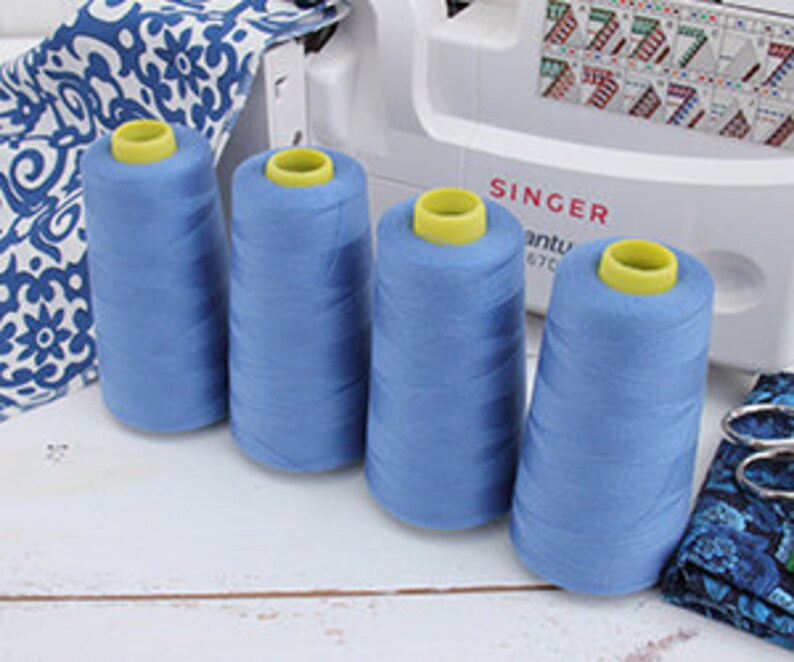 a group of blue spools of thread next to a sewing machine