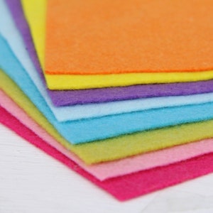 May include: A stack of colorful felt sheets in various shades of pink, green, blue, purple, yellow, and orange. The felt sheets are arranged in a rainbow pattern.