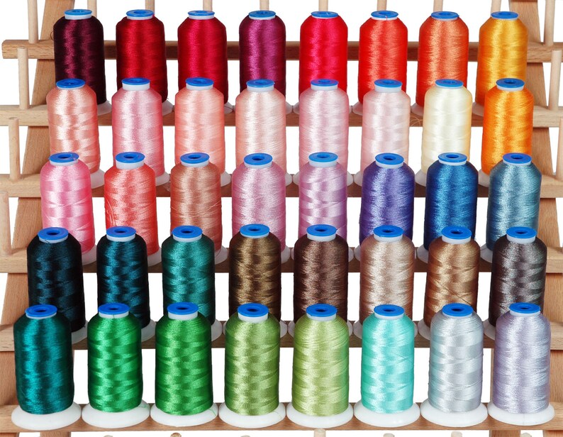 May include: A collection of 48 spools of thread in various colors, arranged on a wooden rack. The spools are all the same size and shape, and they are wound with different colors of thread.
