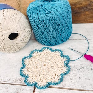 two balls of yarn next to a crochet doily
