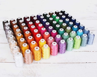 May include: A collection of 50 spools of embroidery thread in a variety of colors, arranged in a triangular shape on a white wooden surface.