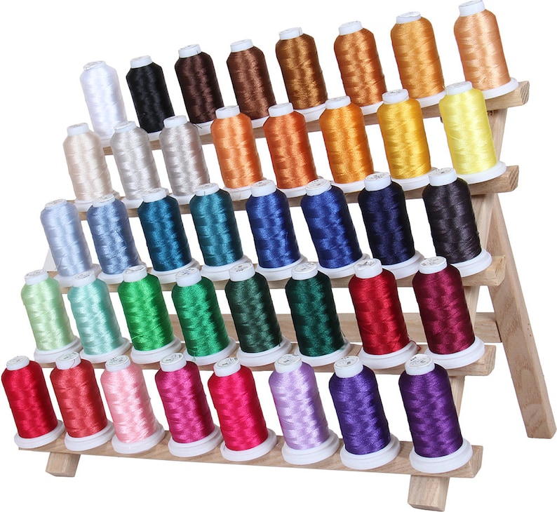 May include: A wooden thread rack with five tiers holds 48 spools of embroidery floss in a variety of colors, including white, beige, blue, green, red, pink, purple, and yellow.