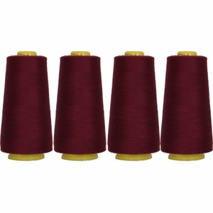 May include: Four spools of maroon sewing thread with yellow plastic bobbins.