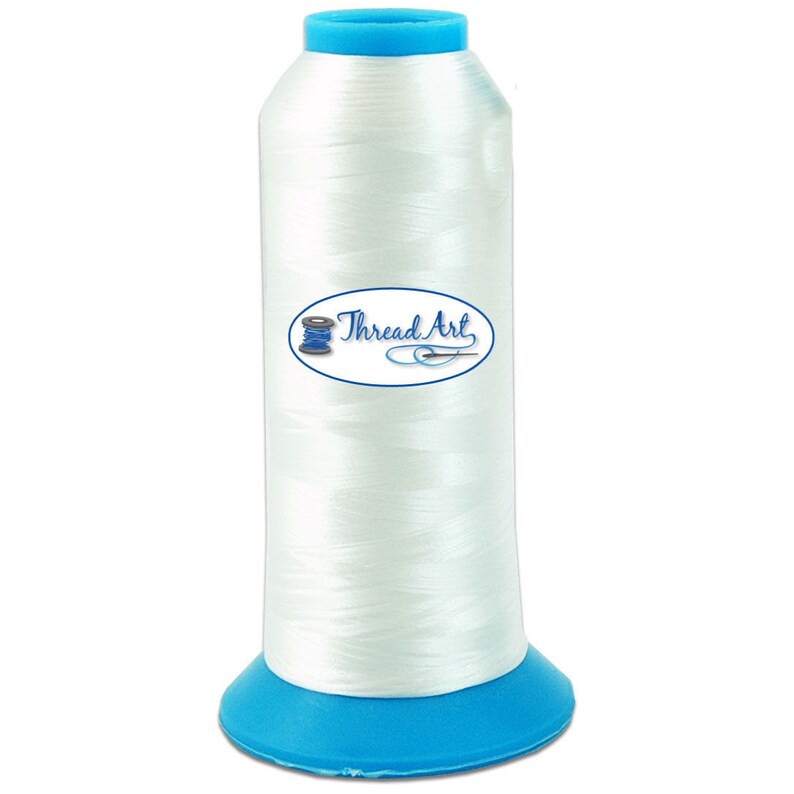 May include: A spool of white thread on a blue plastic bobbin. The spool is labeled "Thread Art".