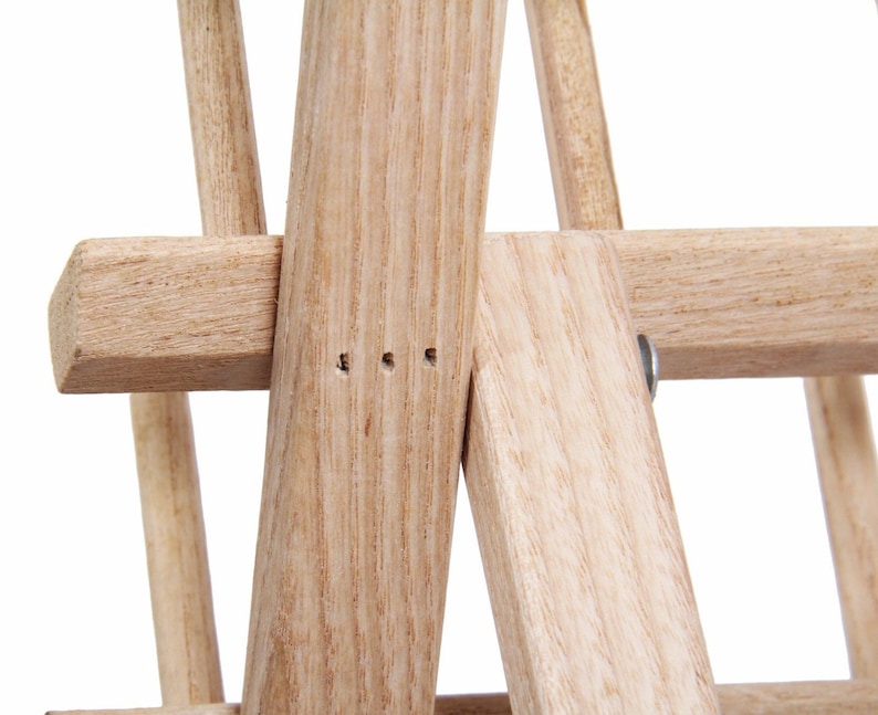 May include: Close-up of a wooden wine rack with a natural finish. The rack is made of sturdy wood and has a simple design. The rack is designed to hold multiple bottles of wine.