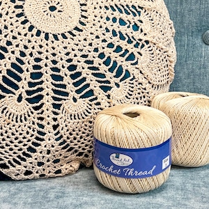 two balls of yarn sitting next to a crochet bag