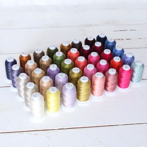 May include: A collection of 40 spools of embroidery thread in various colors, arranged in a triangular pattern. The spools are labeled with numbers.
