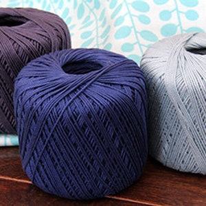 Pu&ograve; includere: Tre gomitoli di filato in diverse tonalit&agrave; di blu. Il filato &egrave; di peso medio e ha una texture liscia.