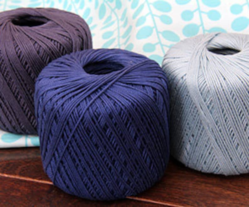 Pu&ograve; includere: Tre gomitoli di filato in diverse tonalit&agrave; di blu. Il filato &egrave; di peso medio e ha una texture liscia.