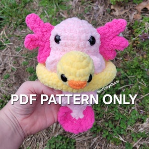 Könnte beinhalten: Ein rosa und gelbes gehäkeltes Amigurumi-Spielzeug eines Axolotls, das einen gelben Entenring trägt. Das Spielzeug wird in einer Hand gehalten. Der Text "PDF PATTERN ONLY" ist am unteren Rand des Bildes sichtbar. @stickychaos ist in der oberen rechten Ecke des Bildes sichtbar.