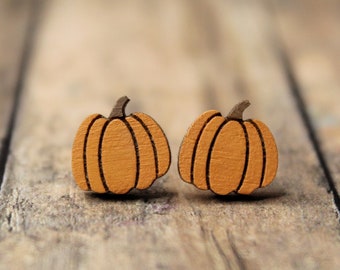May include: A pair of wooden pumpkin earrings. The earrings are orange and have a brown stem.