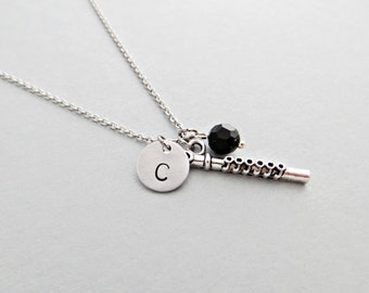 May include: A silver necklace with a silver charm that says "C" and a silver flute charm with a black bead.