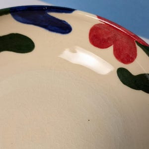 Pode incluir: Uma tigela de cer&acirc;mica branca com um esmalte craquelado. A tigela tem um design abstrato colorido com formas verdes, azuis e vermelhas.