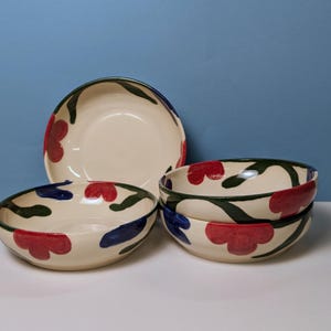Pode incluir: Conjunto de cinco tigelas de cer&acirc;mica com fundo branco e design floral em vermelho, verde e azul.