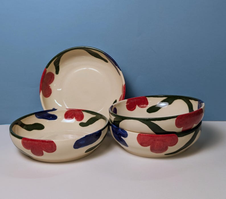 Pode incluir: Conjunto de cinco tigelas de cer&acirc;mica com fundo branco e design floral em vermelho, verde e azul.