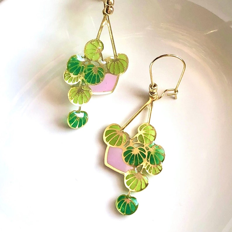 Puede incluir: Pendientes de oro con un dise&ntilde;o de esmalte rosa y verde de una planta colgante. La planta tiene varias hojas y est&aacute; en una maceta peque&ntilde;a.