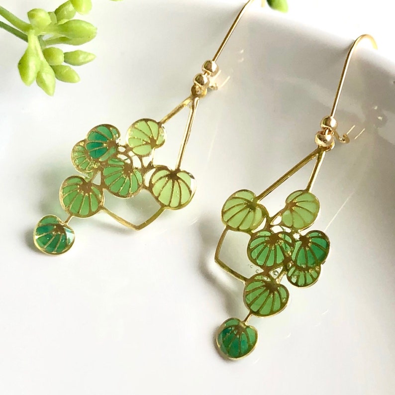 Puede incluir: Pendientes de oro con un dise&ntilde;o geom&eacute;trico con hojas verdes. Los pendientes son de estilo colgante y tienen un aspecto delicado.