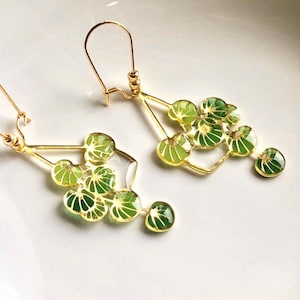 Puede incluir: Pendientes de oro con un dise&ntilde;o geom&eacute;trico que presenta abalorios en forma de hoja verde. Los pendientes son delicados y femeninos.
