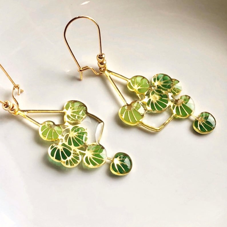 Puede incluir: Pendientes de oro con un dise&ntilde;o geom&eacute;trico que presenta abalorios en forma de hoja verde. Los pendientes son delicados y femeninos.