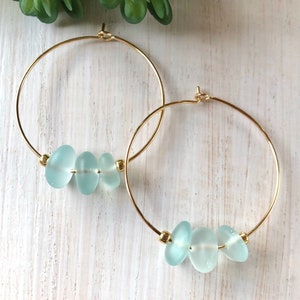May include: Gold hoop earrings with three light blue sea glass beads.