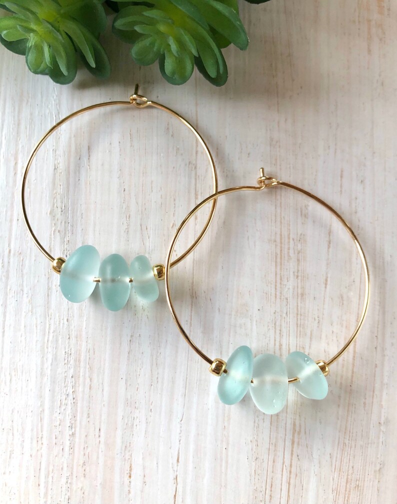 May include: Gold hoop earrings with three light blue sea glass beads.