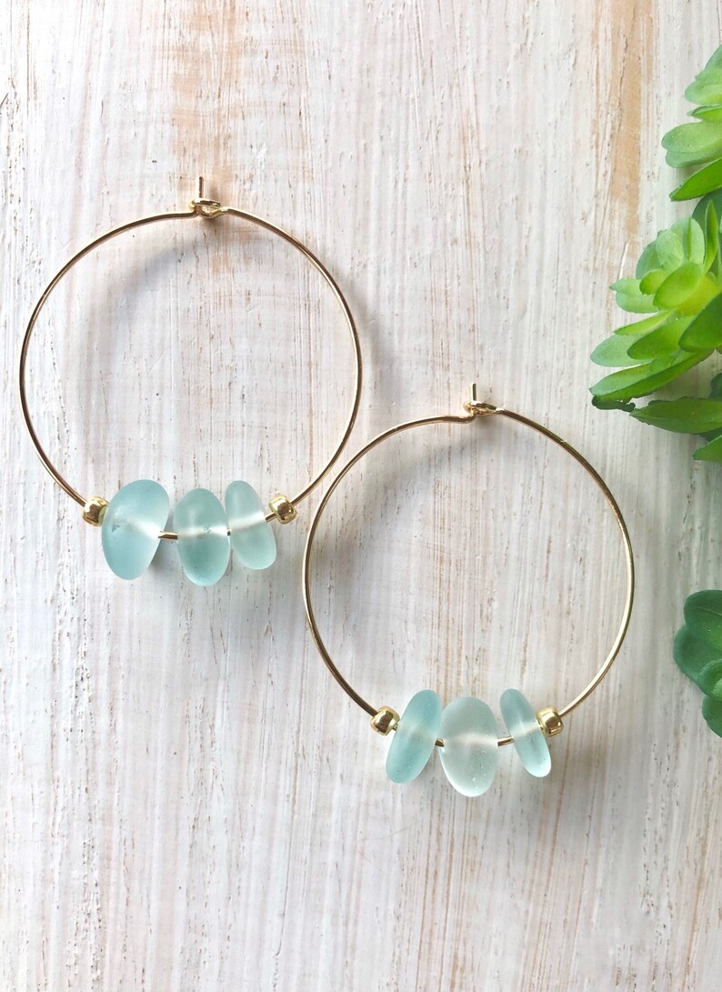 May include: Gold hoop earrings with three light blue sea glass beads on each earring.