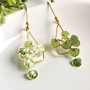 Puede incluir: Pendientes de oro con un dise&ntilde;o geom&eacute;trico con hojas de esmalte verde y blanco. Los pendientes son delicados y femeninos.
